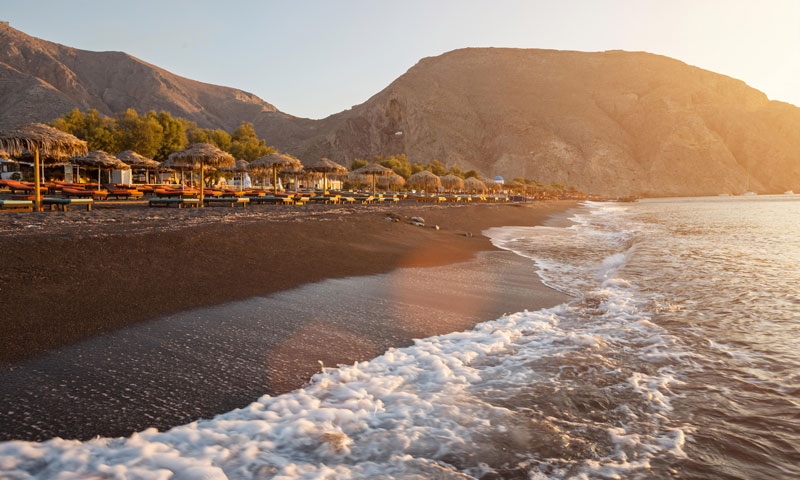 The famous black sandy beach of Perissa in Santorini Greece